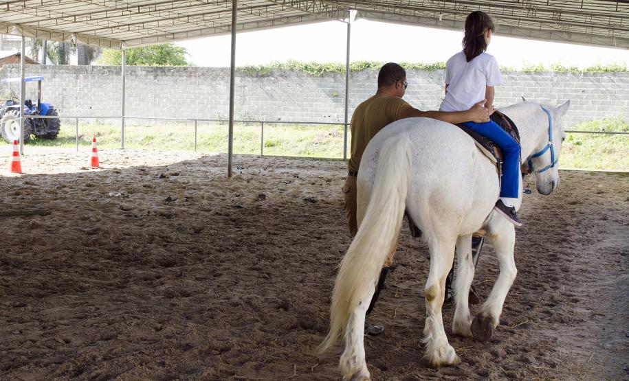 Projeto de equoterapia da Policia Militar Montada do Paraná Projeto de equoterapia da Policia Militar Montada do Paraná. Na foto: Maria Eduarda Ramos. sendo auxiliada pelo fisioterapeuta Geter Kleink. Curitiba, 16-09-2015. Foto: Adrieli Takiguti /SEDS